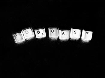 White computer keys forming the words “Podcast” against a black backdrop.