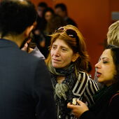 Three participants of the event are standing in the midst of other people and are talking