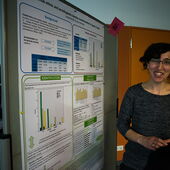 A participant stands in front of a poster and smiles
