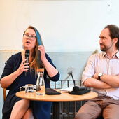 Kaja Skowrońska and Sébastien François sit on a podium, Kaja Skowrońska speaks into a microphone.
