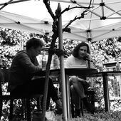 Eva Geulen und Joshua Groß sitzen nebeneinander auf einer kleinen Bühne und unterhalten sich.