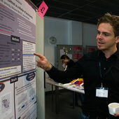 One participant points to a poster and explains