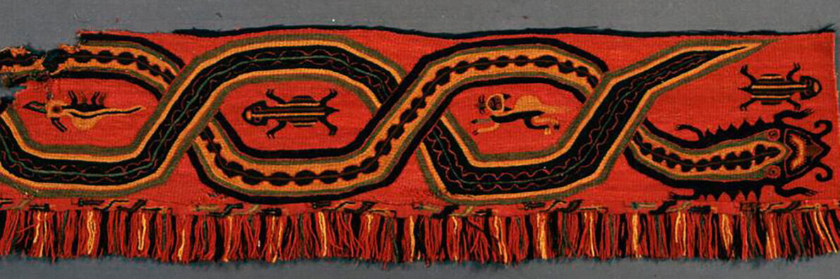 Red textile band with black and orange geometric ornaments and stylized animal figures, finished with fringes along the lower edge.