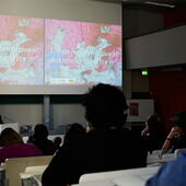 Das Publikum hört einem Vortrag zu, über dem Vortragenden an der Wand sieht man eine Präsentation mit einer Landkarte und dem Titel »Urban fragmentation(s). BORDERS & IDENTITY III«