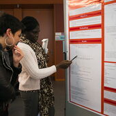 Solace Yankson points to a poster with a pen and explains a diagram