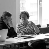 Black and white photograph of two female conferees, they are sitting and discussing.