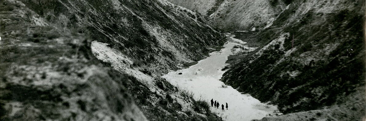 Schwarz-weiß-Foto der Schlucht von Babyn Jar mit fünf menschlichen Gestalten.