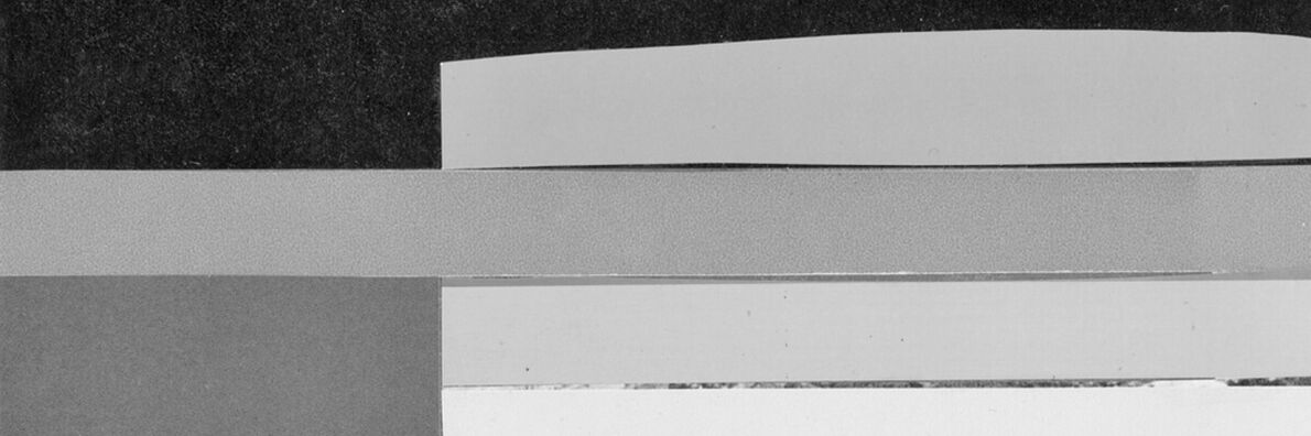 Negative image of a bridge arch made of stone with water flowing under it.