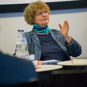 Monika Walter sitzt und gestikuliert mit ihrer linken Hand.