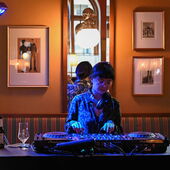 DJ Saeko Killy at a mixing desk, illuminated by blue light.