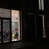 Blick von der Straße in den Veranstaltungsraum, es sind voll besetzte Publikumsreihen zu sehen.