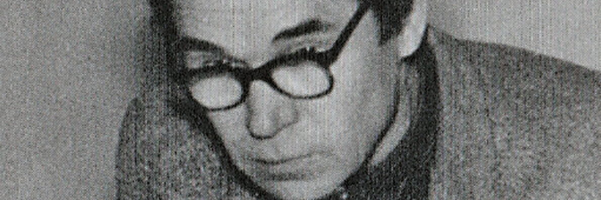Black and white portrait photo of Georgi Demidov with dark horn-rimmed glasses.
