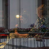 Elias Hirschl speaks into a microphone, Hanna Hamel listens to him. The two can be seen through a window.