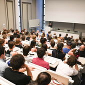 View from the top of a full lecture hall. Maggie Nelson stands at the front and addresses the audience.