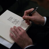 Stephan Thome signs his novel “Fliehkräfte,” you can only see the open book, his hands and a ballpoint pen