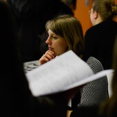 A participant of the event sits and thinks, in the foreground you can see a blurred event brochure