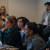 A participant in the audience asks a question, others listen