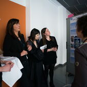 Several participants stand by a small table and look at a poster