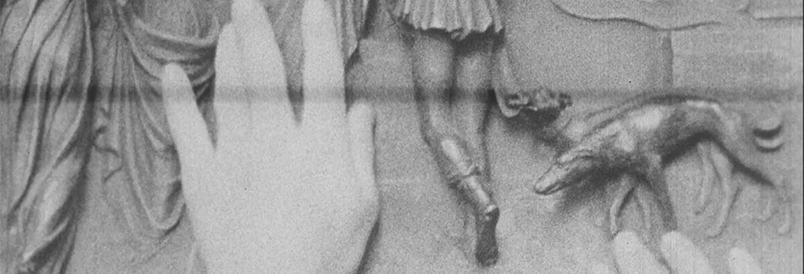 Zwei Hände betasten ein Relief, auf dem mehrer menschliche Unterkörper von hinten und ein Hund an der Leine zu sehen sind.