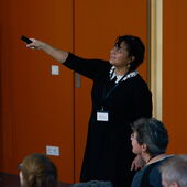 Norma Mendoza-Denton recites, aiming a small remote at the screen while the audience listens