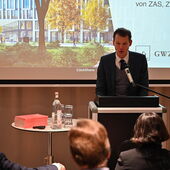 André Lottmann steht am Rednerpult und spricht zum Publikum.