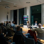 Vier Personen diskutieren auf einem Podium vor Publikum.