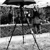 Janika Gelinek spricht in ein Mikrofon. Hinter ihr auf einer kleinen Bühne sitzen Christina Ernst und Jackie Thomae.