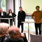 Vier Personen stehen vor der Leinwand und schauen zum Publikum.