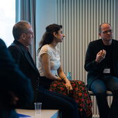 Rudolf Gaudio, Sanaa Alimia and Stefan Willer sit on tables, Stefan Willer speaks