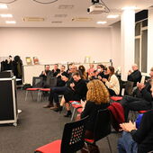 Moderator Ernst Müller and award winner Georg Simmerl stand at the speaker’'s desk. The audience applauds.