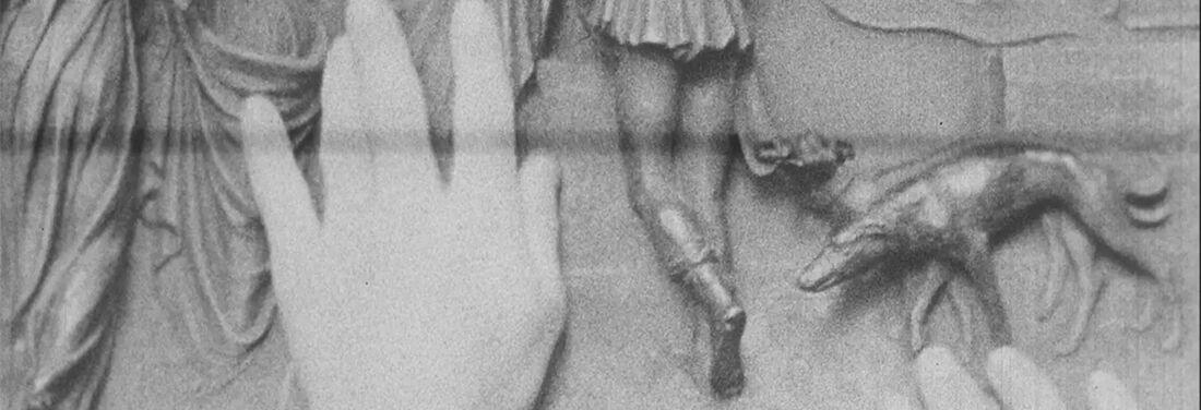 Two hands touch a relief on which several human lower bodies can be seen from behind and a dog on a leash.