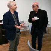 Michael Bienert und Detlev Schöttker unterhalten sich. Bienert gestikuliert, Schöttker hält eine Kaffeetasse mit Untertasse in der Hand.