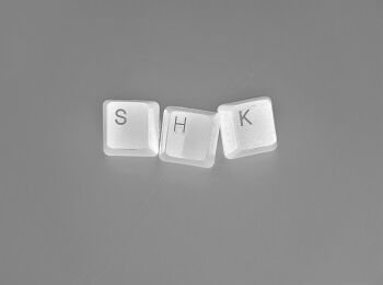 Weiße Computertasten auf grauem Hintergrund, die den Schriftzug »SHK« bilden.