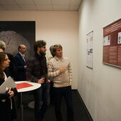 Eine Gruppe von Teilnehmer*innen steht vor zwei Plakaten an der Wand und bespricht sie