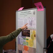 A wall with posters, a participant points to the poster