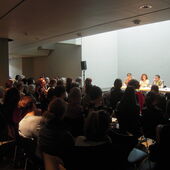 Authors sit on a podium and speak in front of an audience.