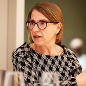 Franziska Brychcy sitzt und spricht nach rechts gewendet, vor ihr sind unscharf drei Wassergläser zu sehen.