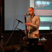 The musician Adi Gelbart plays the saxophone on a stage.