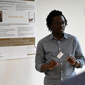 Burrhus Njanjo steht vor seinem Poster zum Thema »Identitätsfigurationen« und spricht zum Publikum.