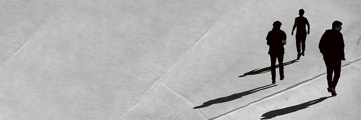 On a gray background, the outlines of three people and their shadows can be seen on the right-hand side of the picture, walking away from the person looking at them.