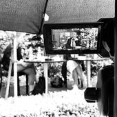 Auf einem Kameradisplay ist Jackie Thomae zu sehen. Im Hintergrund sieht man verschwommen zwei Personen.