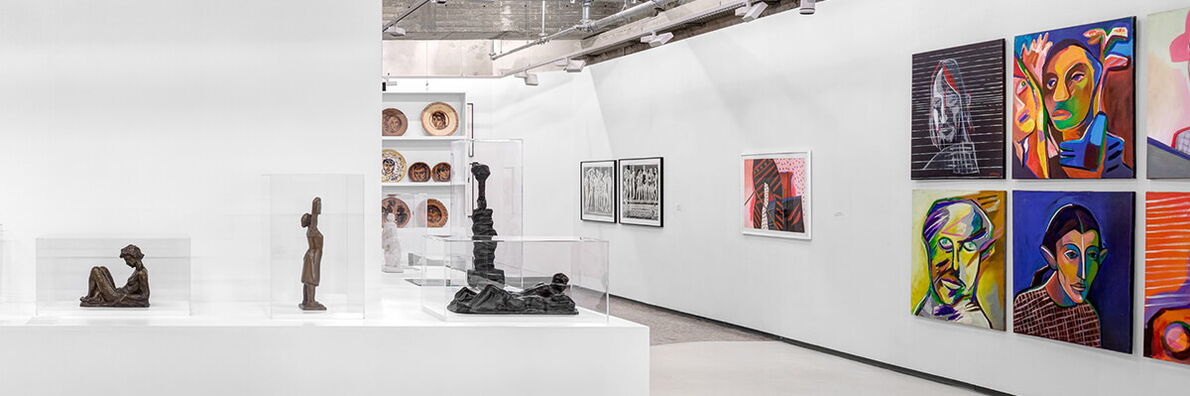 Ausstellungsraum mit Skulpturen, Keramiktellern und Holzschnitten und bunten Malereien.