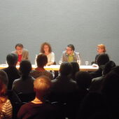 The four authors sit on a podium. Falko Schmieder speaks to the audience.