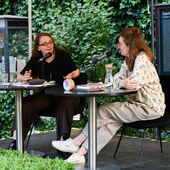 Emma Braslavsky and Hanna Hamel sit on a stage talking animatedly to each other.