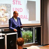 Hinrich Schmidt-Henkel hält einen Vortrag bei der Konferenz, hinter ihm die Power-Point-Präsentation mit dem Tagungstitel (Stil und Moral)