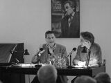 Black and white photograph of Claudio Magris and xxx during a lecture. The two are sitting on a podium and Claudio Magris is speaking and gesticulating.