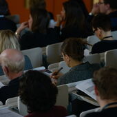 Das Publikum der Konferenz hört zu und schreibt mit