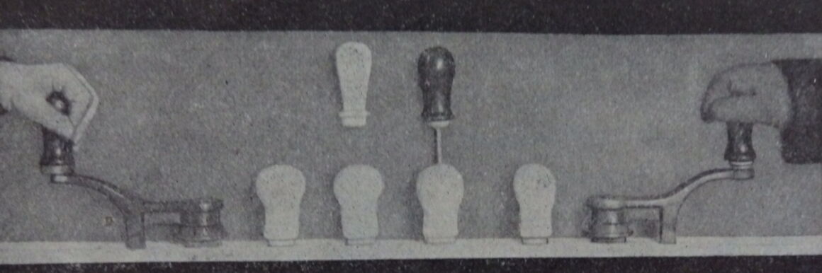 Black and white photo. A series of prototypes for handle shapes. On the left and right edges of the image is a hand, each of which is embracing and trying out a handle.