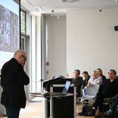 Detlev Schöttker stands at the lectern and speaks to the audience.