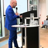 Claude Haas steht am Rednerpult und spricht ins Mikrofon.